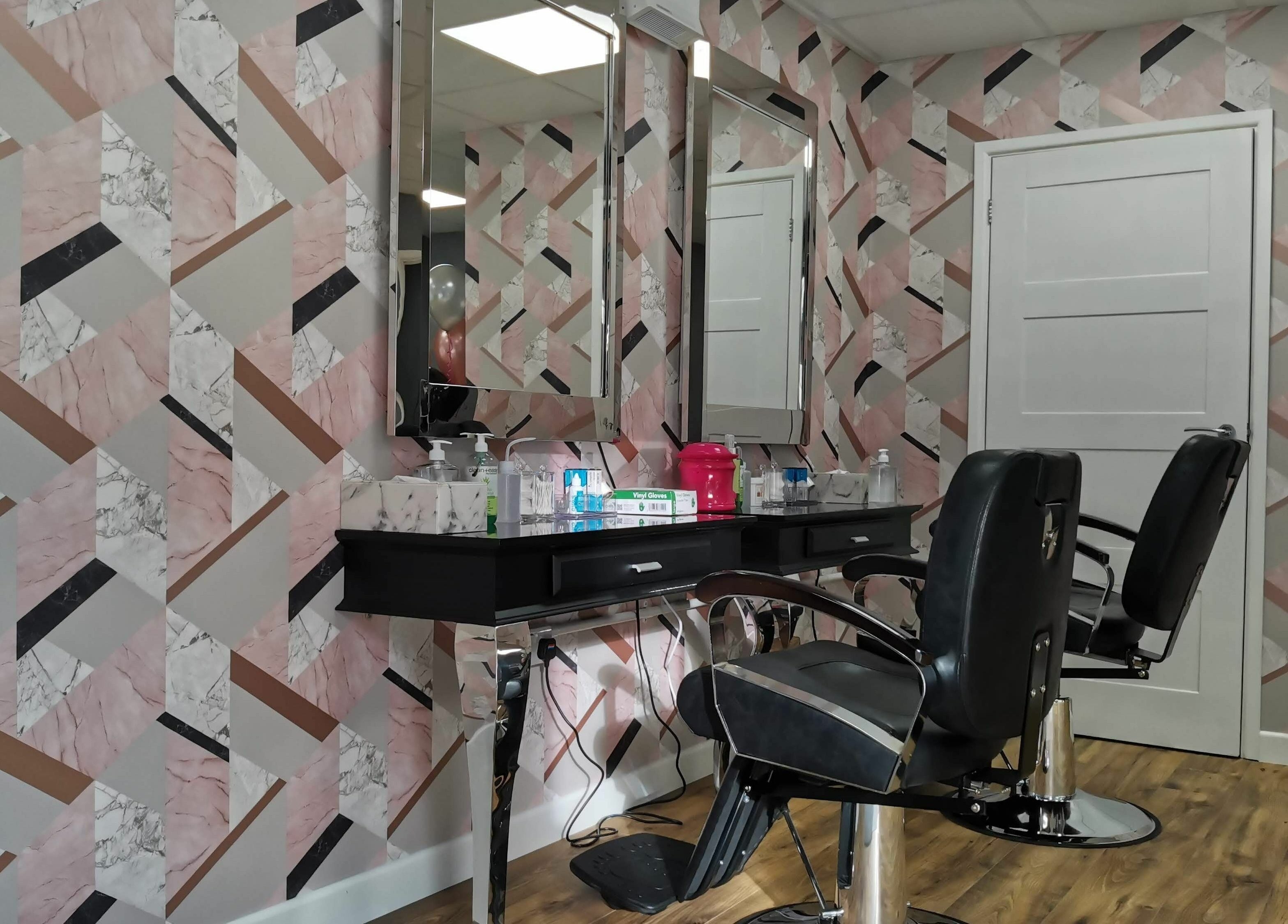 Elegant salon chairs and mirrored station at Glowfinity - Wokingham, GB, with geometric wall design.