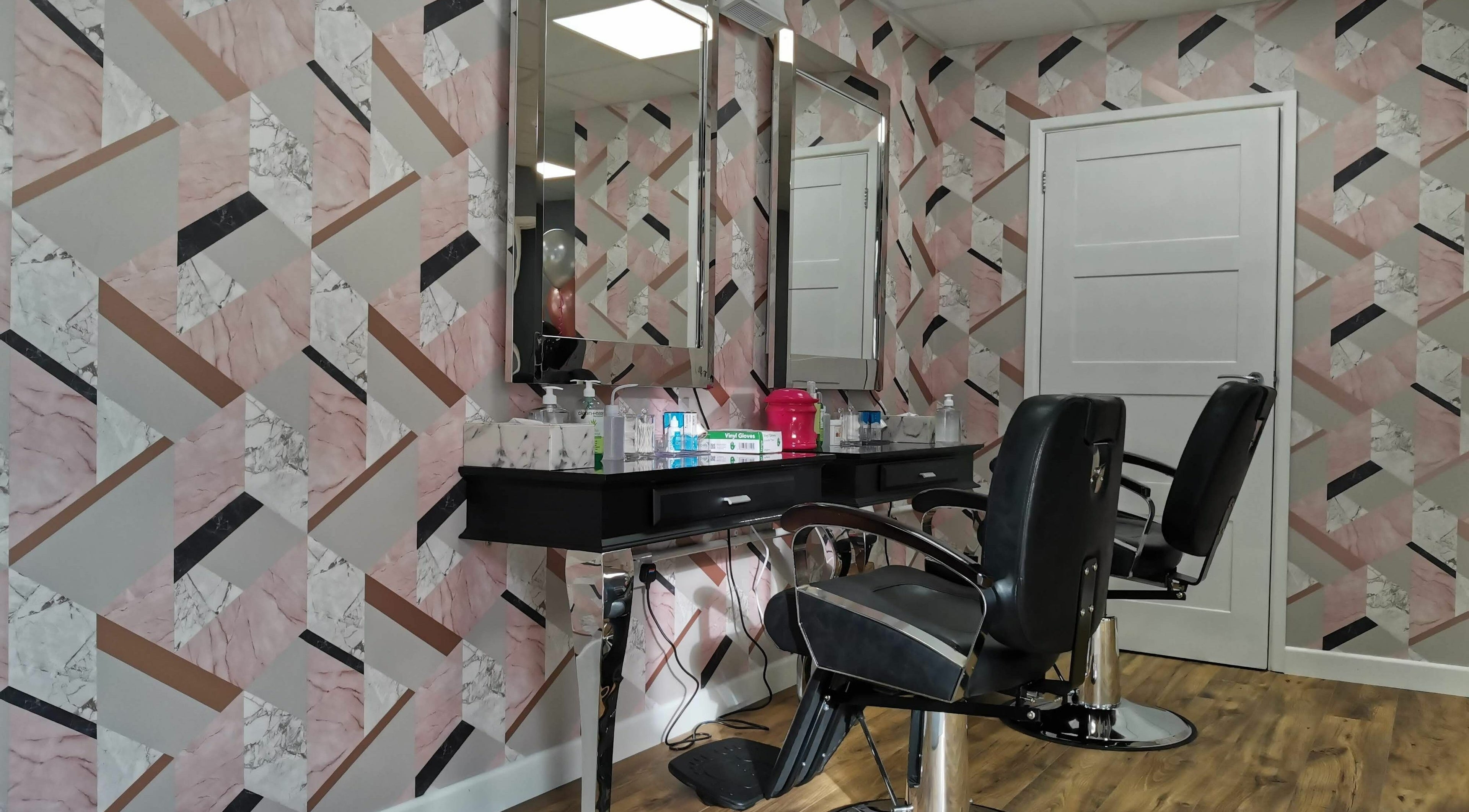 Elegant salon chairs and mirrored station at Glowfinity - Wokingham, GB, with geometric wall design.