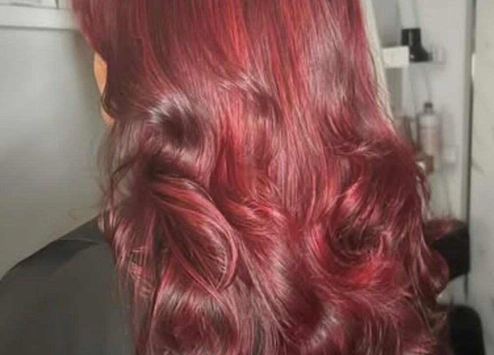 Vibrant red hair styled in curls at Ruby Alice Hair, Broughton, England, GB.