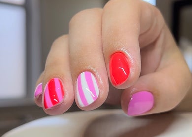 Vibrant nail art at Beauty Muse (BLEND), Skewen, Wales, GB. Pink and red designs on freshly manicured nails.