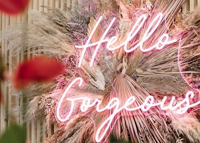 Neon sign 'Hello Gorgeous' amidst flowers at Laura Bell Salon, Falmouth, England, GB.
