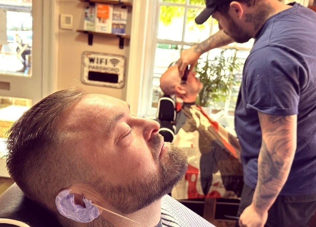 Inside Barbers on the Green Rowlands Castle, a customer receives a relaxing shave. Rowlands Castle, England, GB.