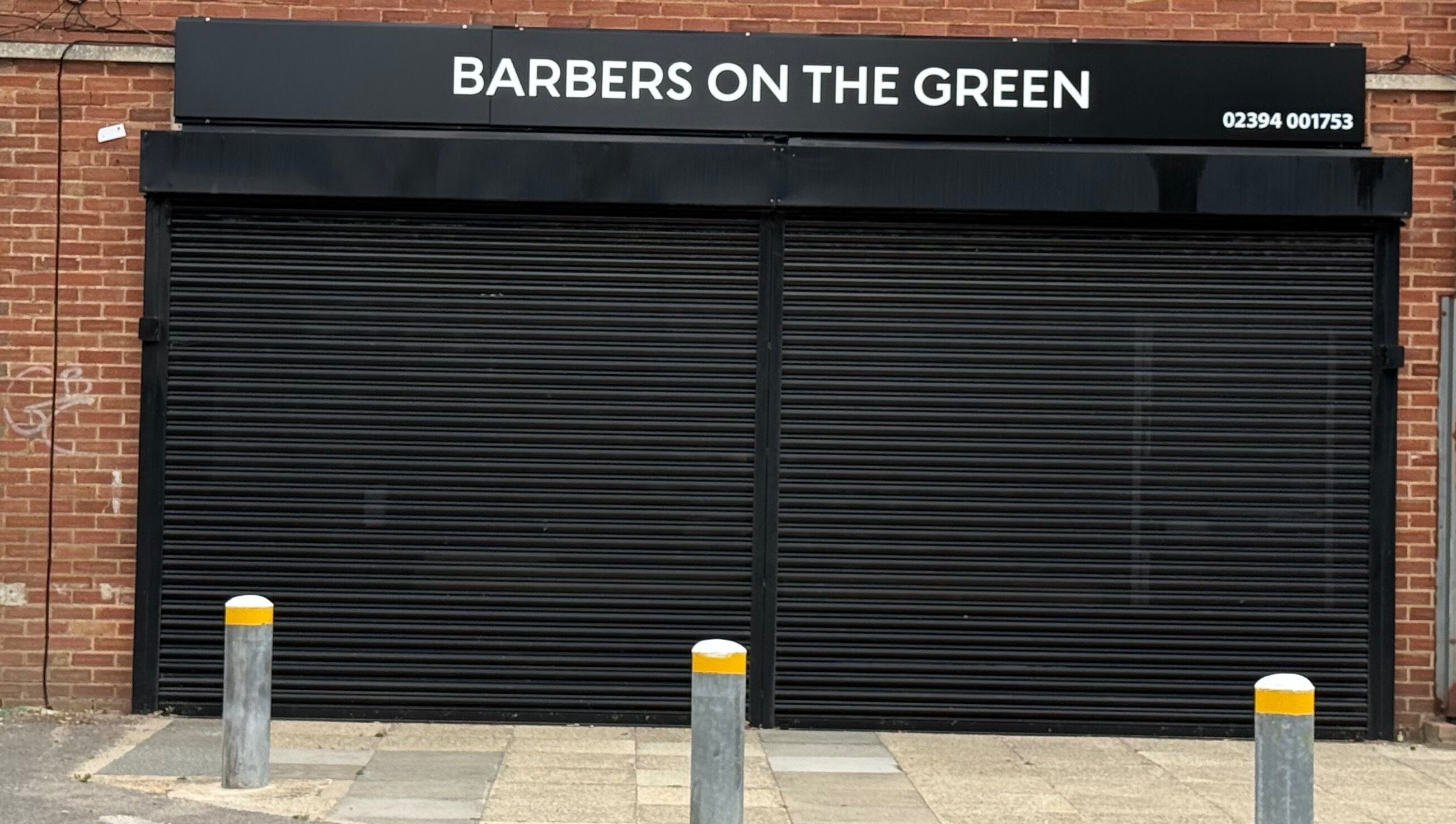 Barbers On The Green storefront with closed shutters in Havant, England, GB.