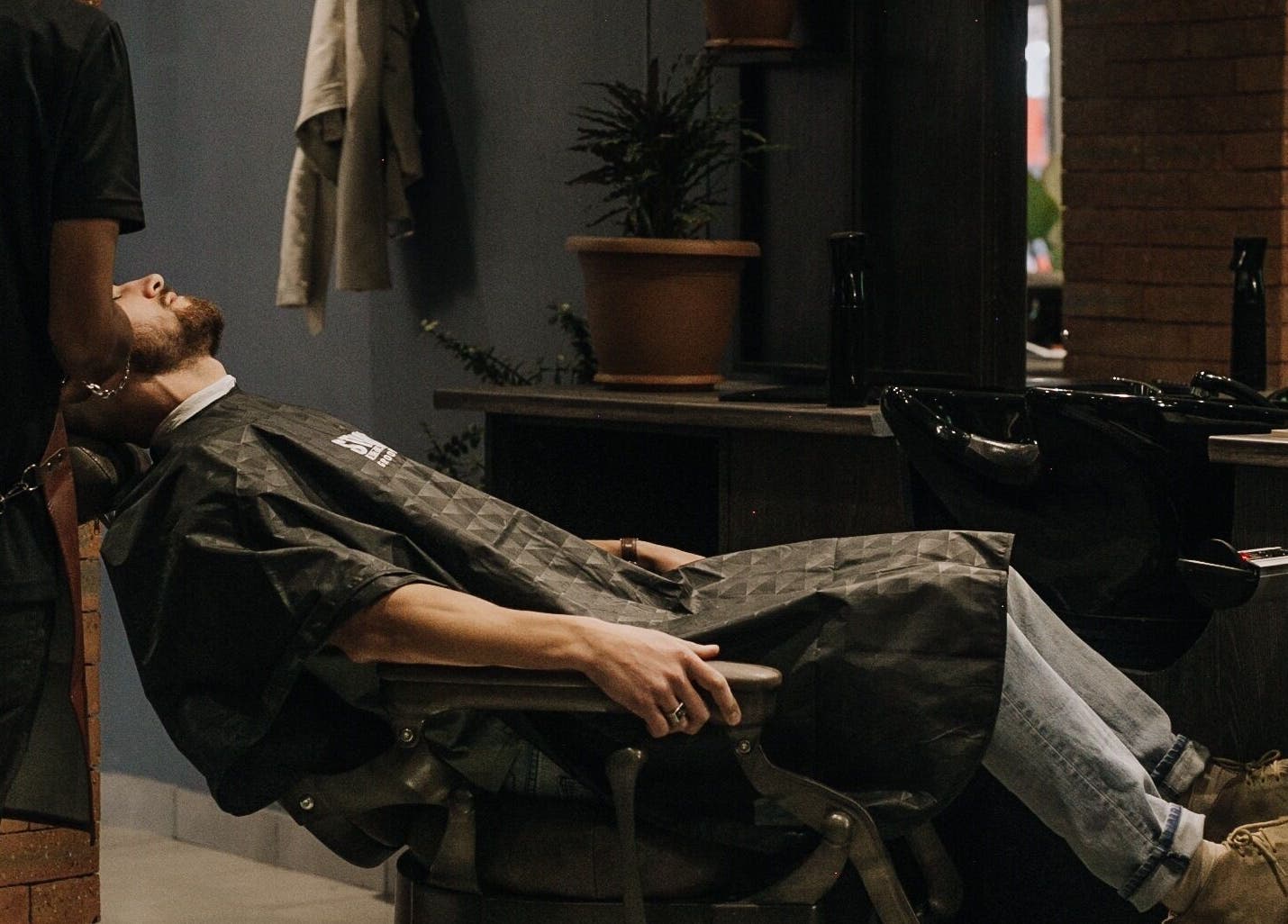 Client in barber chair receiving haircut at The Art of Man, Pretoria, Gauteng, ZA.