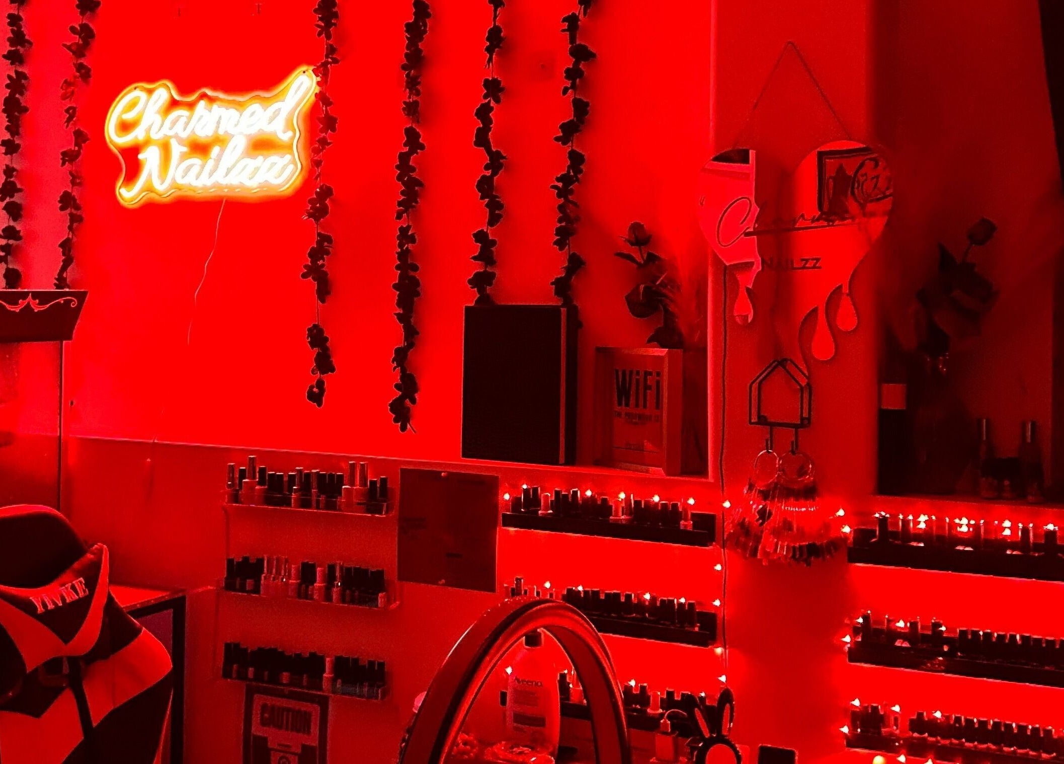 Charmed Nailzz interior with vibrant red lights in Red Deer, Alberta, CA, showcasing nail polish display.