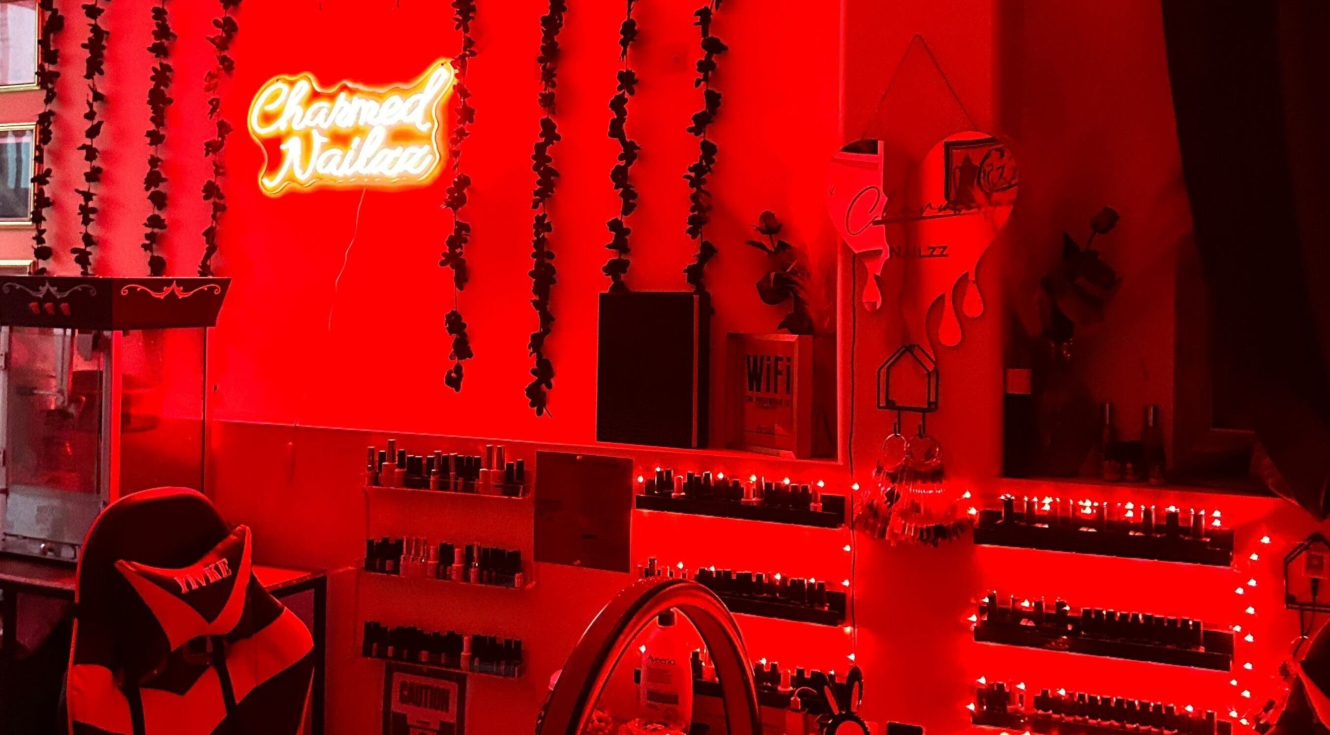 Charmed Nailzz interior with vibrant red lights in Red Deer, Alberta, CA, showcasing nail polish display.