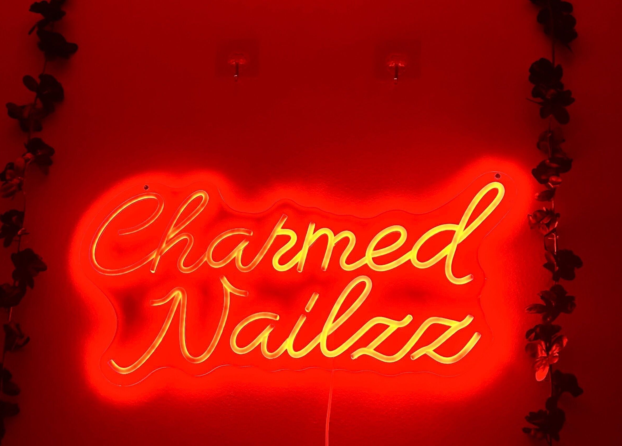 Neon sign at Charmed Nailzz in Red Deer, Alberta, CA burns brightly against a decorative backdrop.