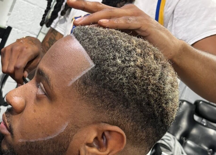 Barber styling a man's hair at Den Of Sauce in Lathrup, Michigan, US.