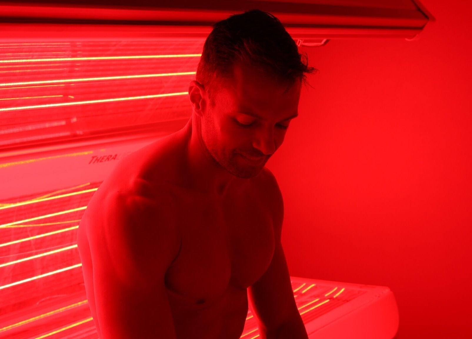 Man enjoying infrared therapy at Super-Young in Armadale, Victoria, AU in a soothing red-lit room.