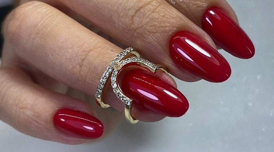 Manicura roja brillante en Mely Nail Art, La Habana, La Habana, CU, con elegante anillo dorado.
