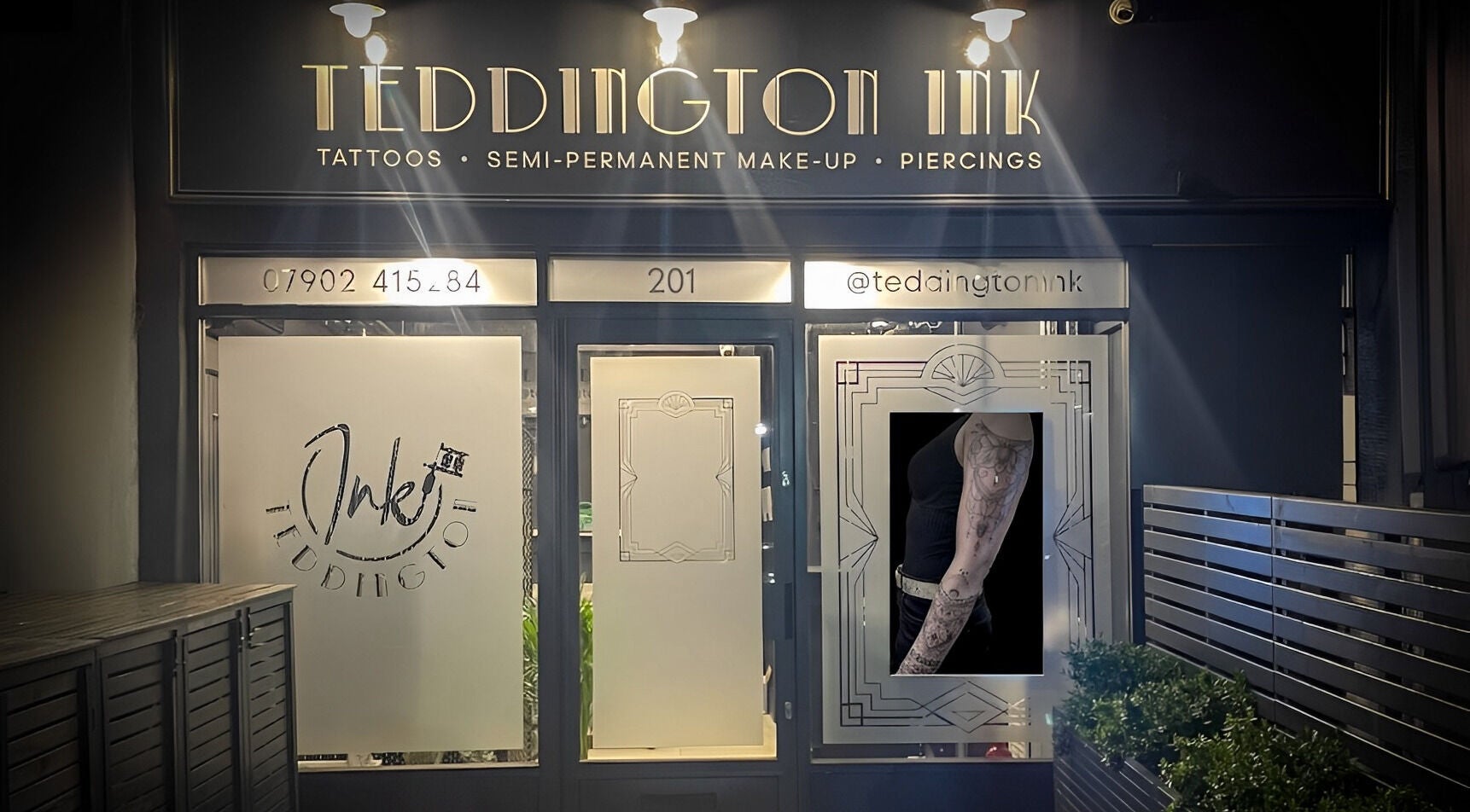Teddington Ink's illuminated storefront in Teddington, England, GB showcasing tattoos and body art.