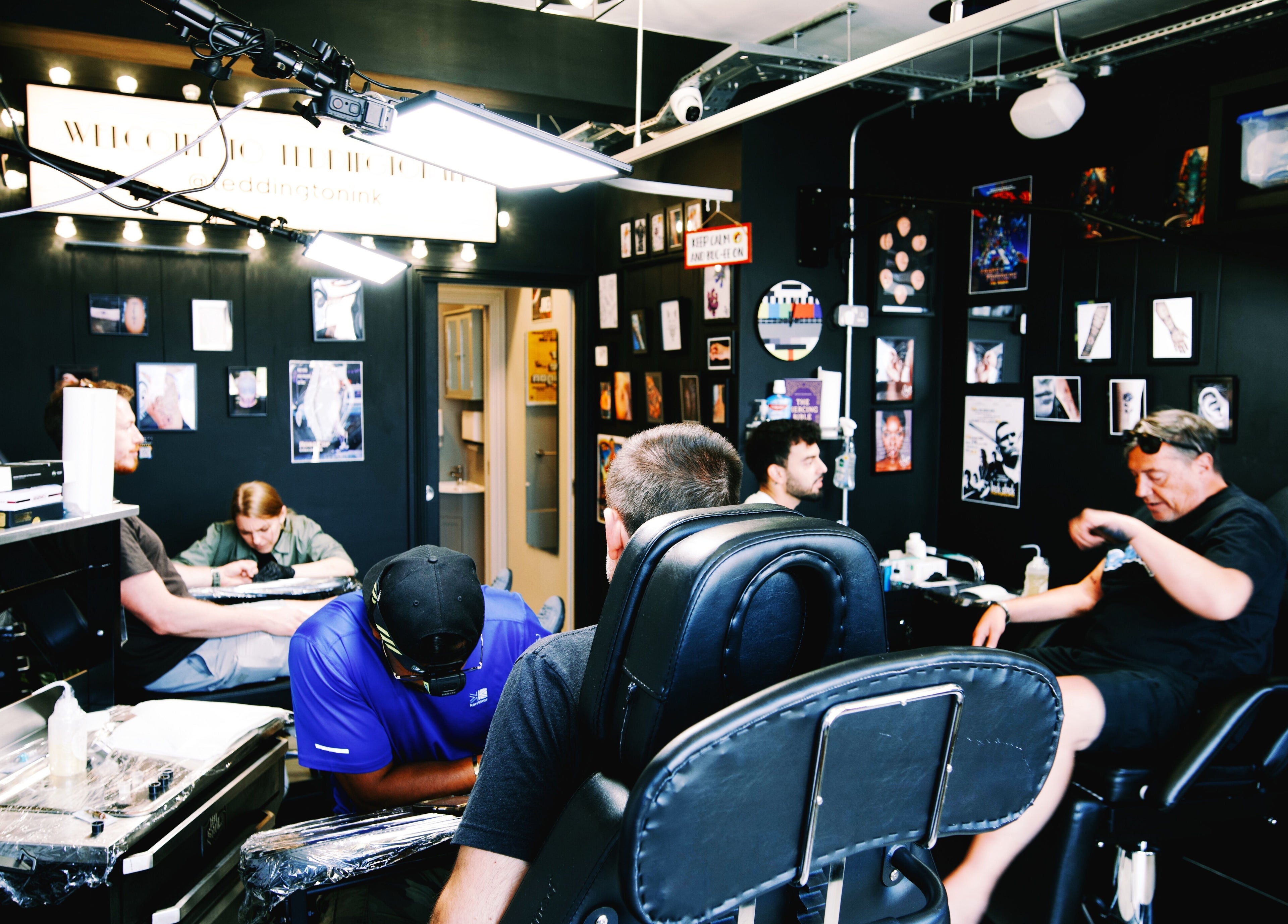 Inside Teddington Ink, a lively tattoo studio in Teddington, England, GB with artists at work.
