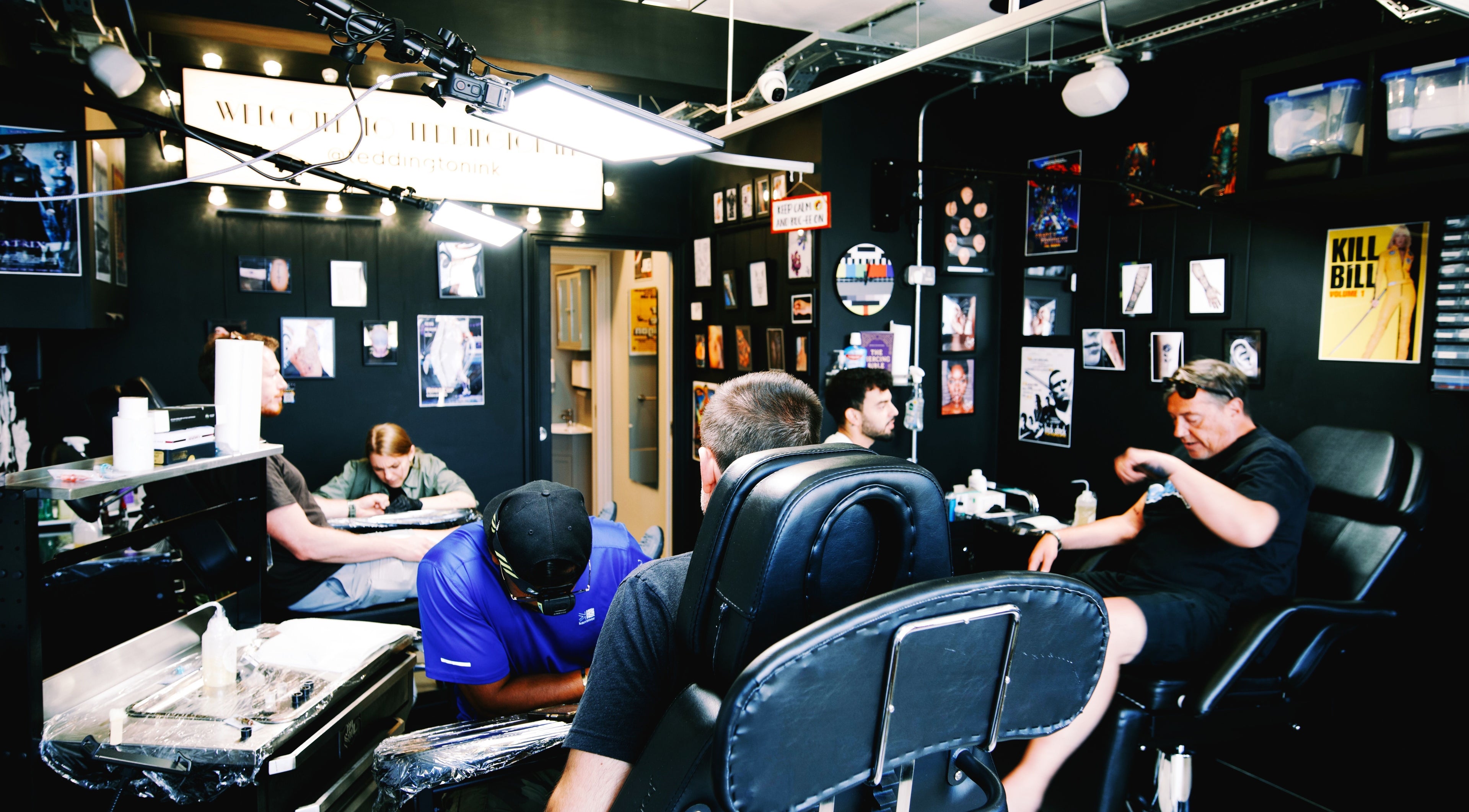 Inside Teddington Ink, a lively tattoo studio in Teddington, England, GB with artists at work.
