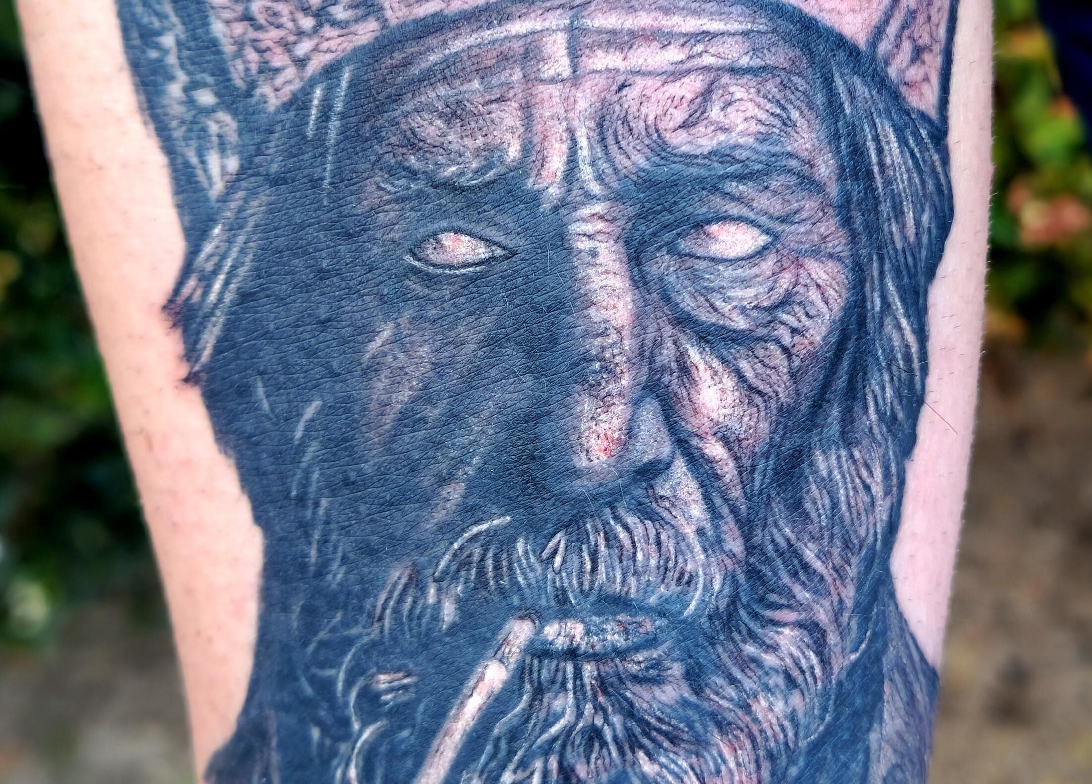 Detailed tattoo of a mythical face at Teddington Ink, located in Teddington, England, GB.