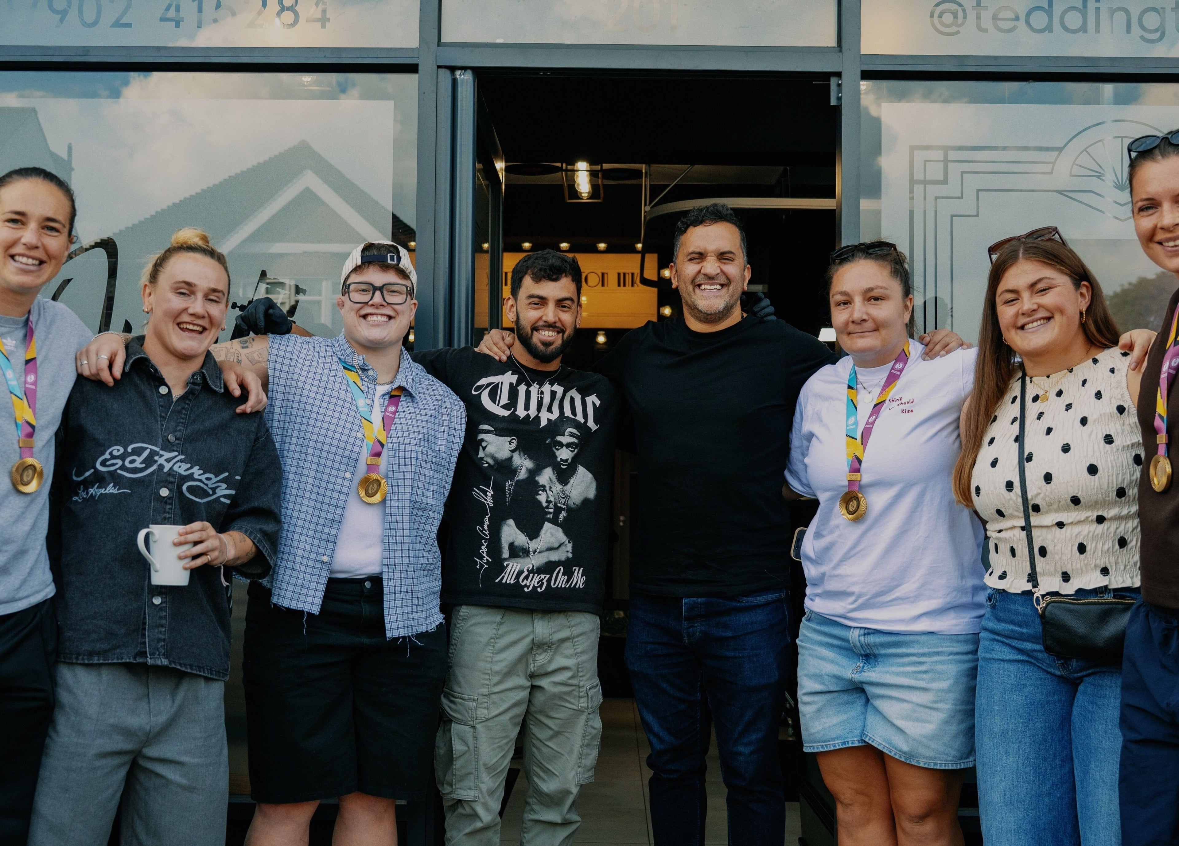 Group of happy people with medals in front of Teddington Ink, Teddington, England, GB.