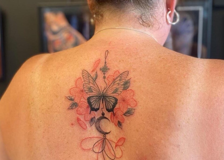 Elegant butterfly tattoo with floral design at Teddington Ink, Teddington, England, GB.