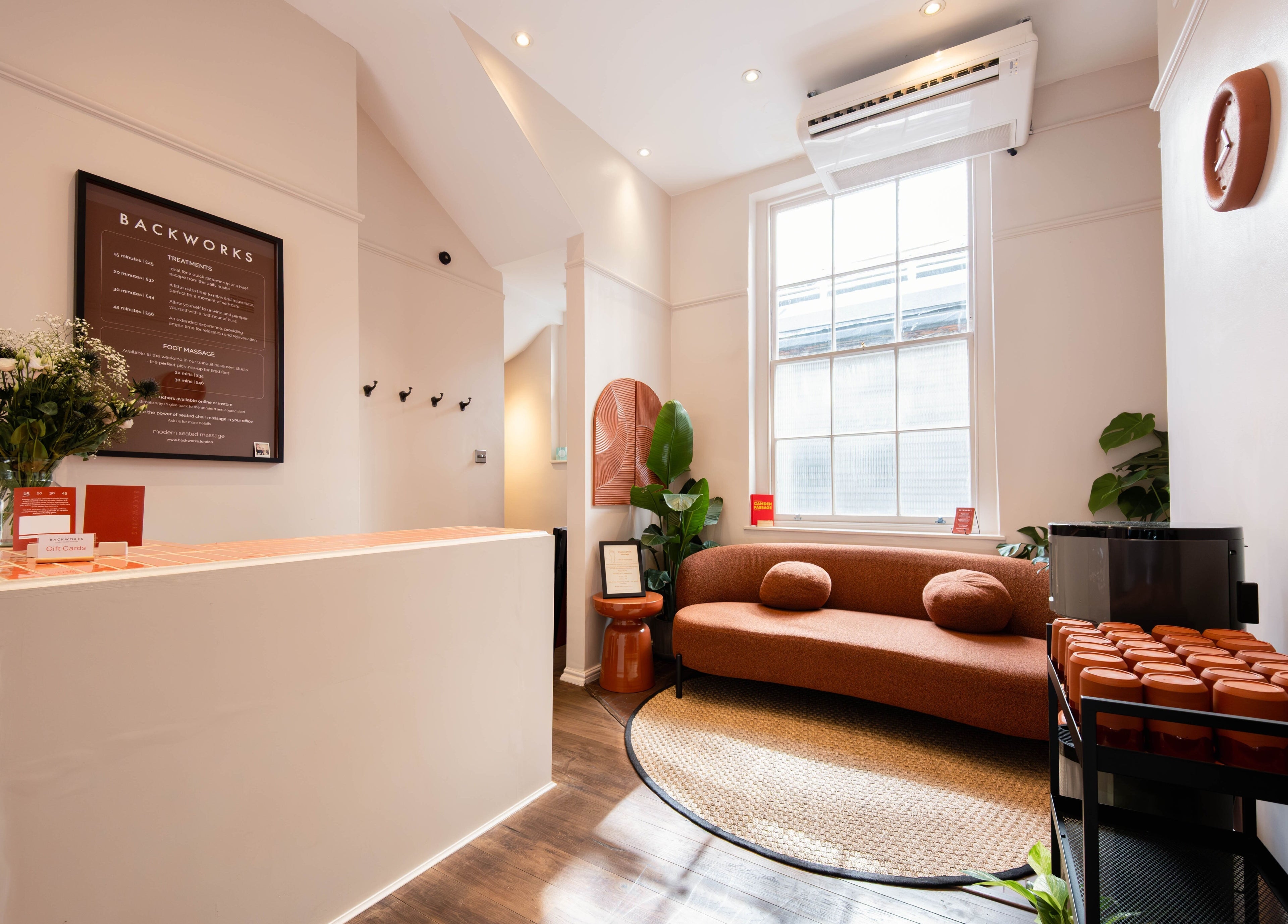 Chic interior of Backworks, London, GB, showcasing modern decor with a cozy seating area and flower arrangement.