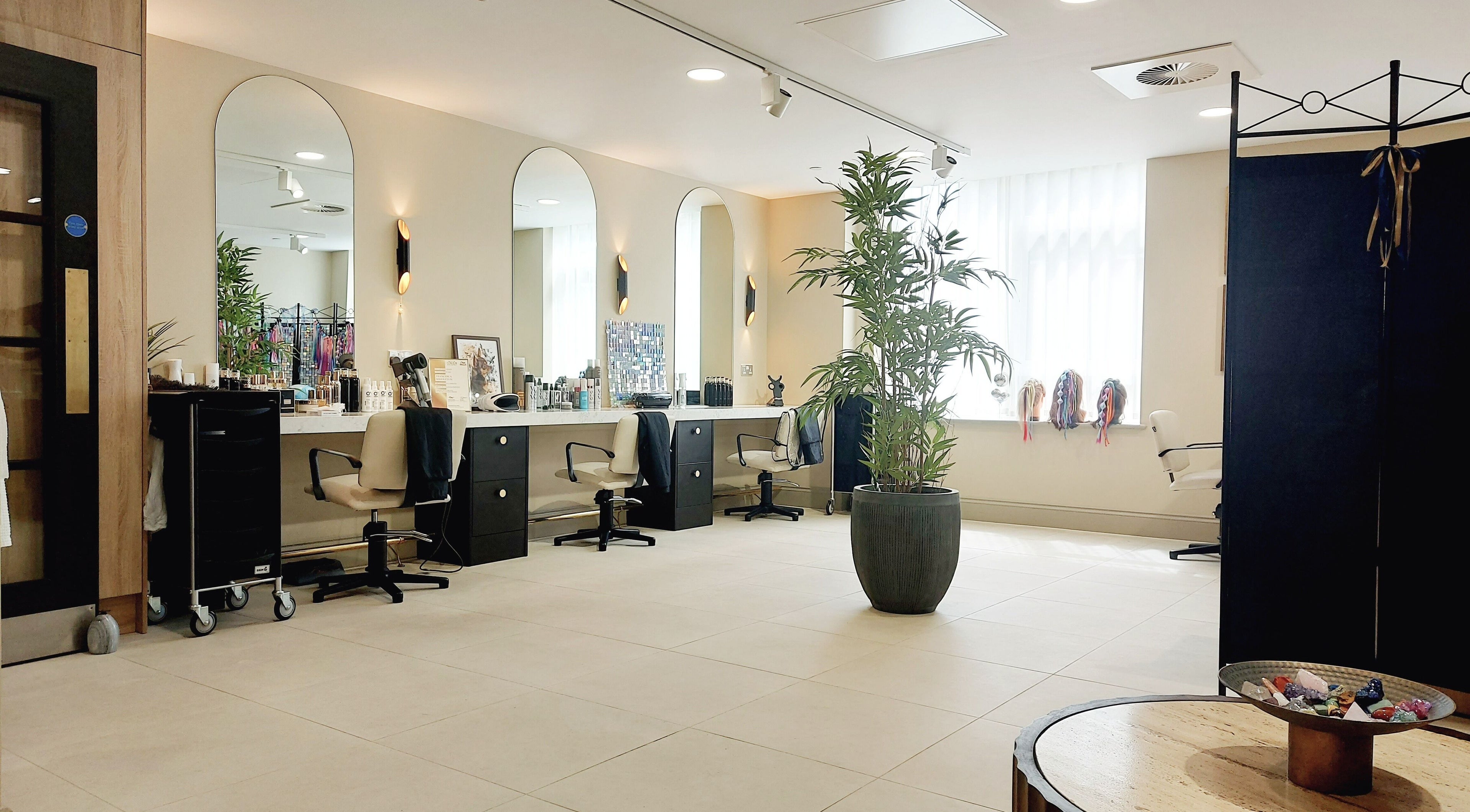Modern interior of Topaz Haircare Salon & Hair Spa in Lyne, England, GB with elegant styling stations and decor.