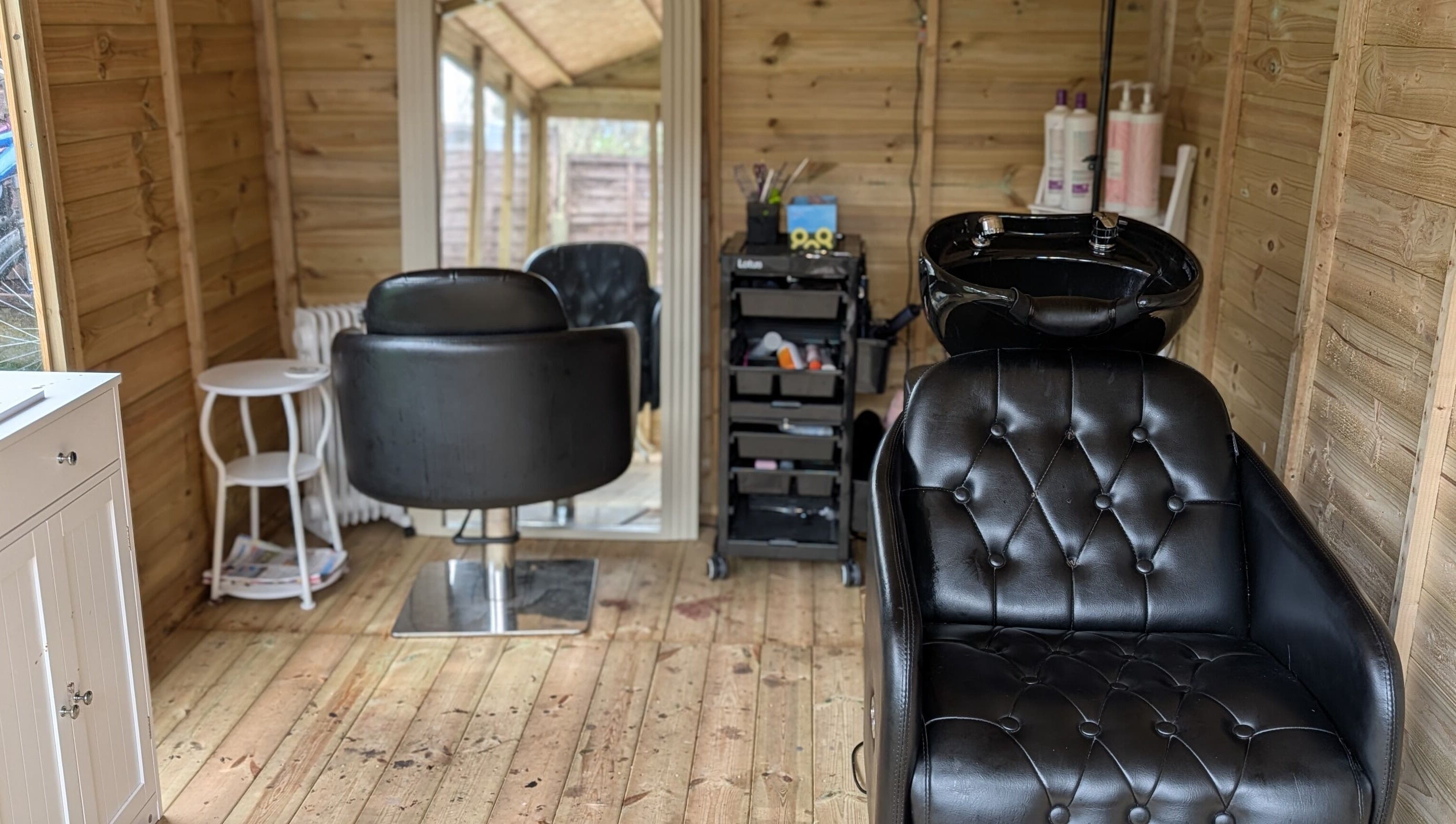 Modern salon interior at Hairlo, Swinton, England, GB featuring stylish black styling chairs and a washing station.