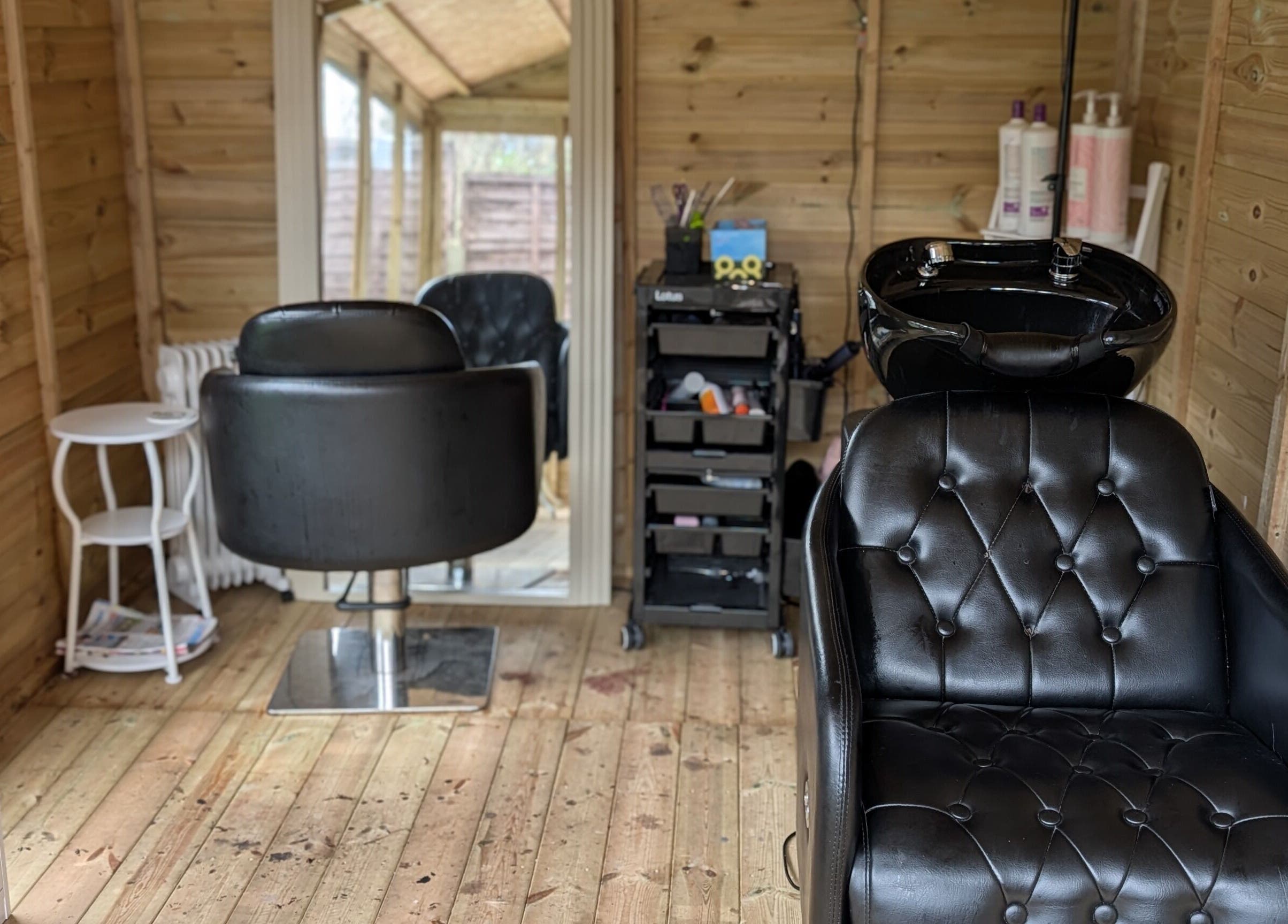 Modern salon interior at Hairlo, Swinton, England, GB featuring stylish black styling chairs and a washing station.
