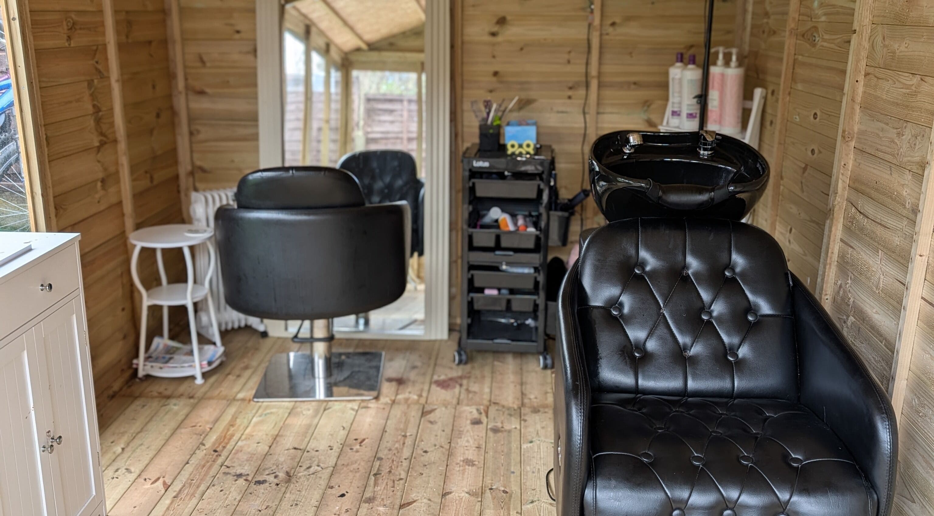 Modern salon interior at Hairlo, Swinton, England, GB featuring stylish black styling chairs and a washing station.