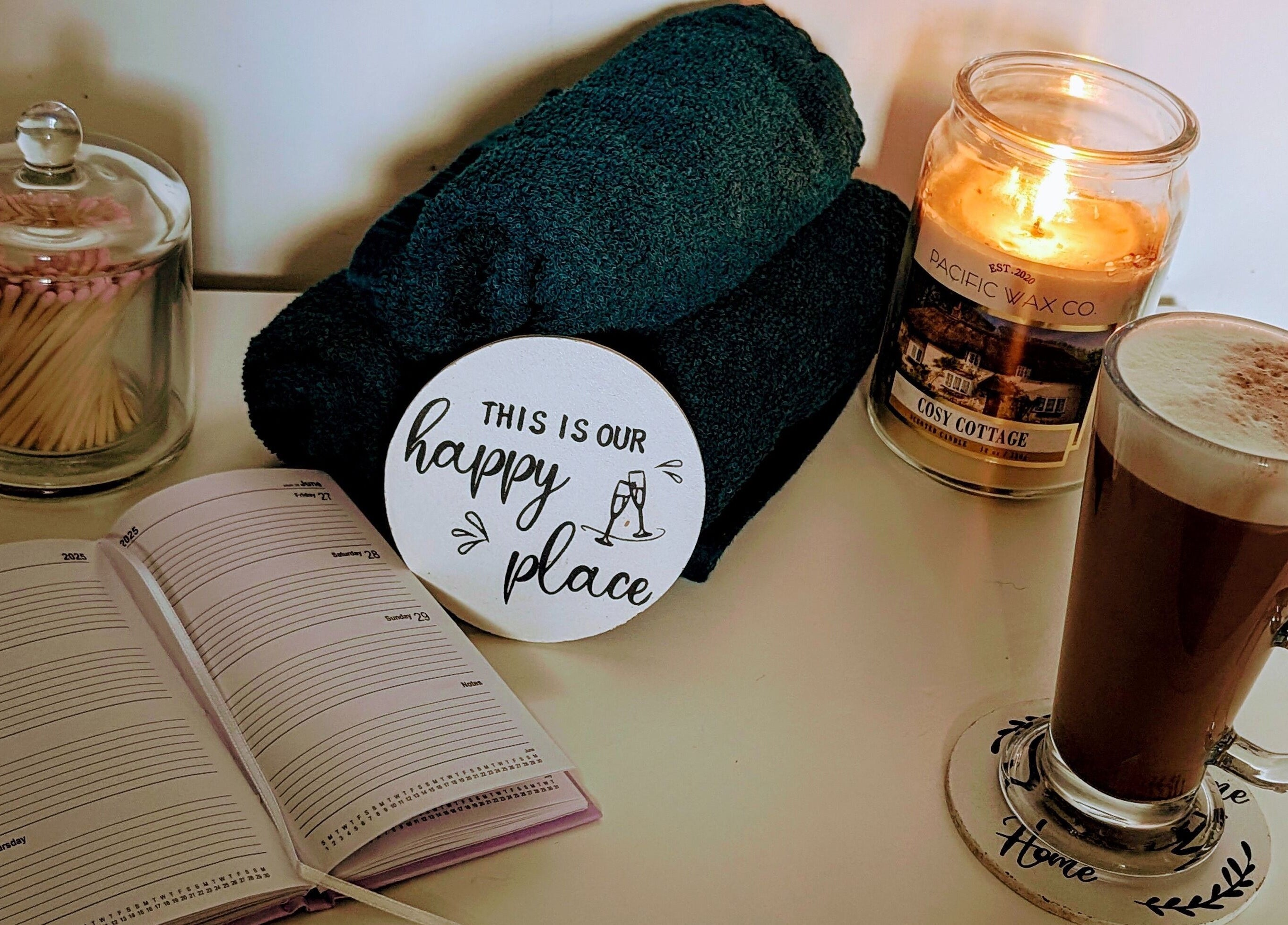 Relaxing setup at Hairlo, Swinton with candle, coffee, towels, and planner for a soothing experience.