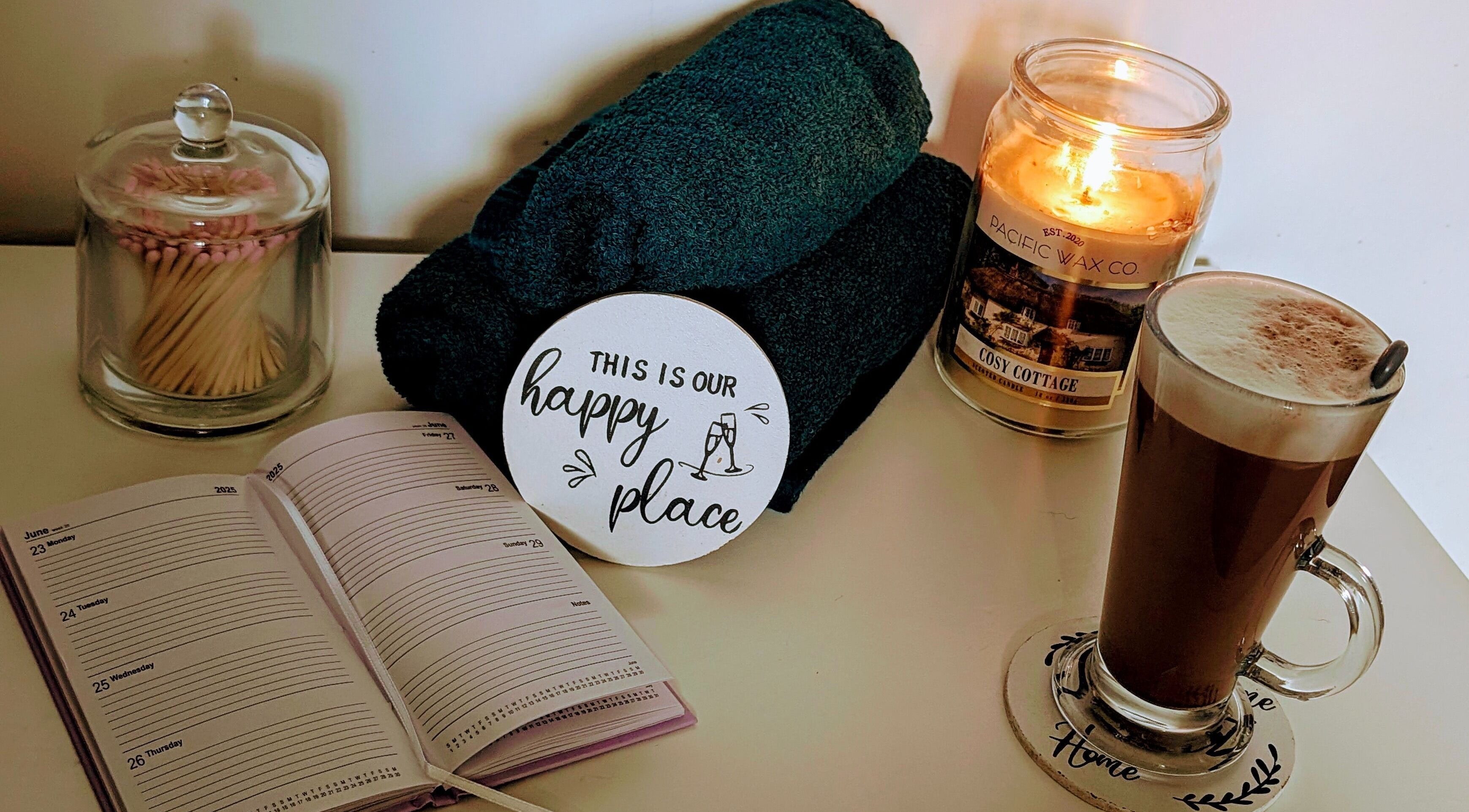 Relaxing setup at Hairlo, Swinton with candle, coffee, towels, and planner for a soothing experience.