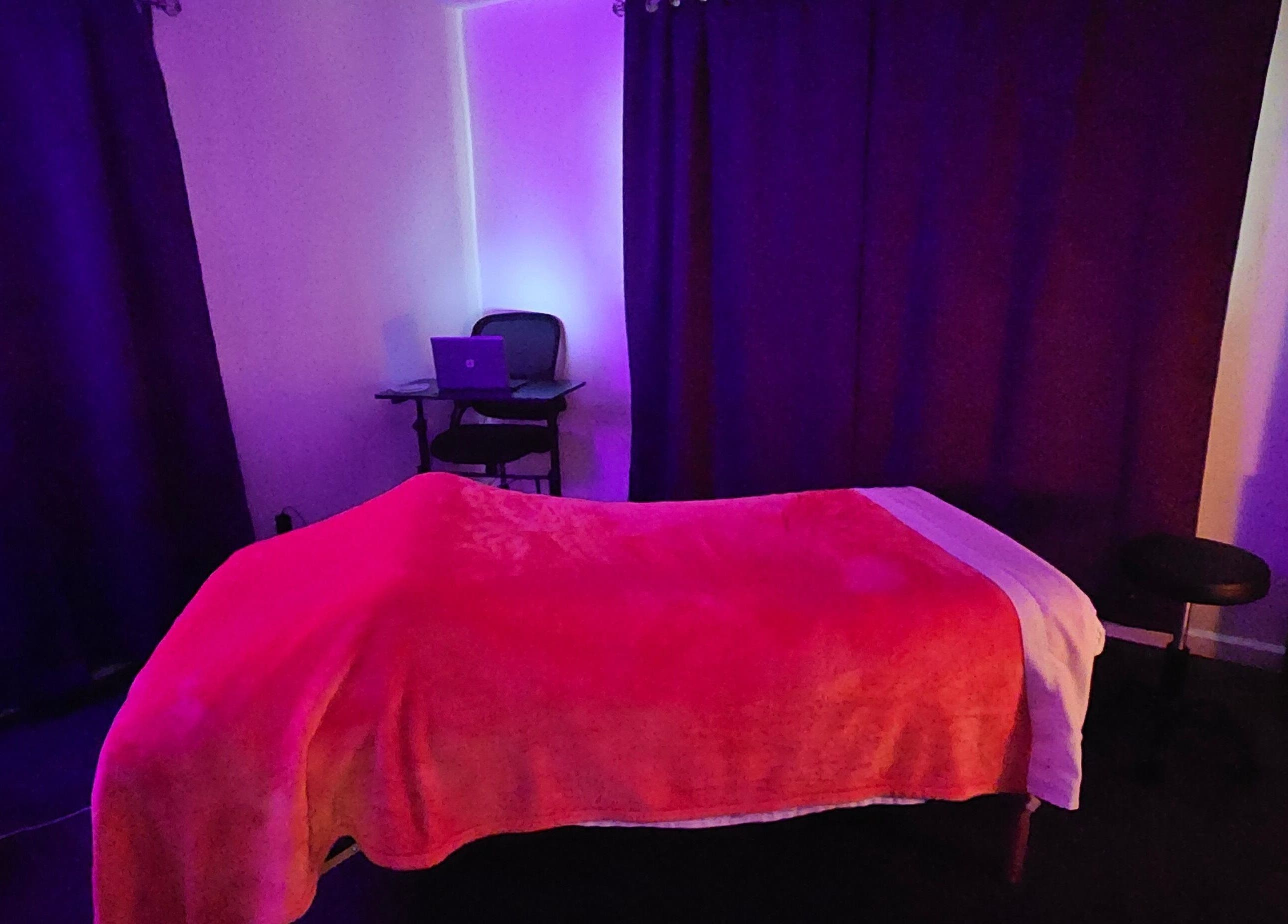 Soothing massage room at Sherna's Synchronicities, LLC, California, Maryland, US with calming purple and red tones.