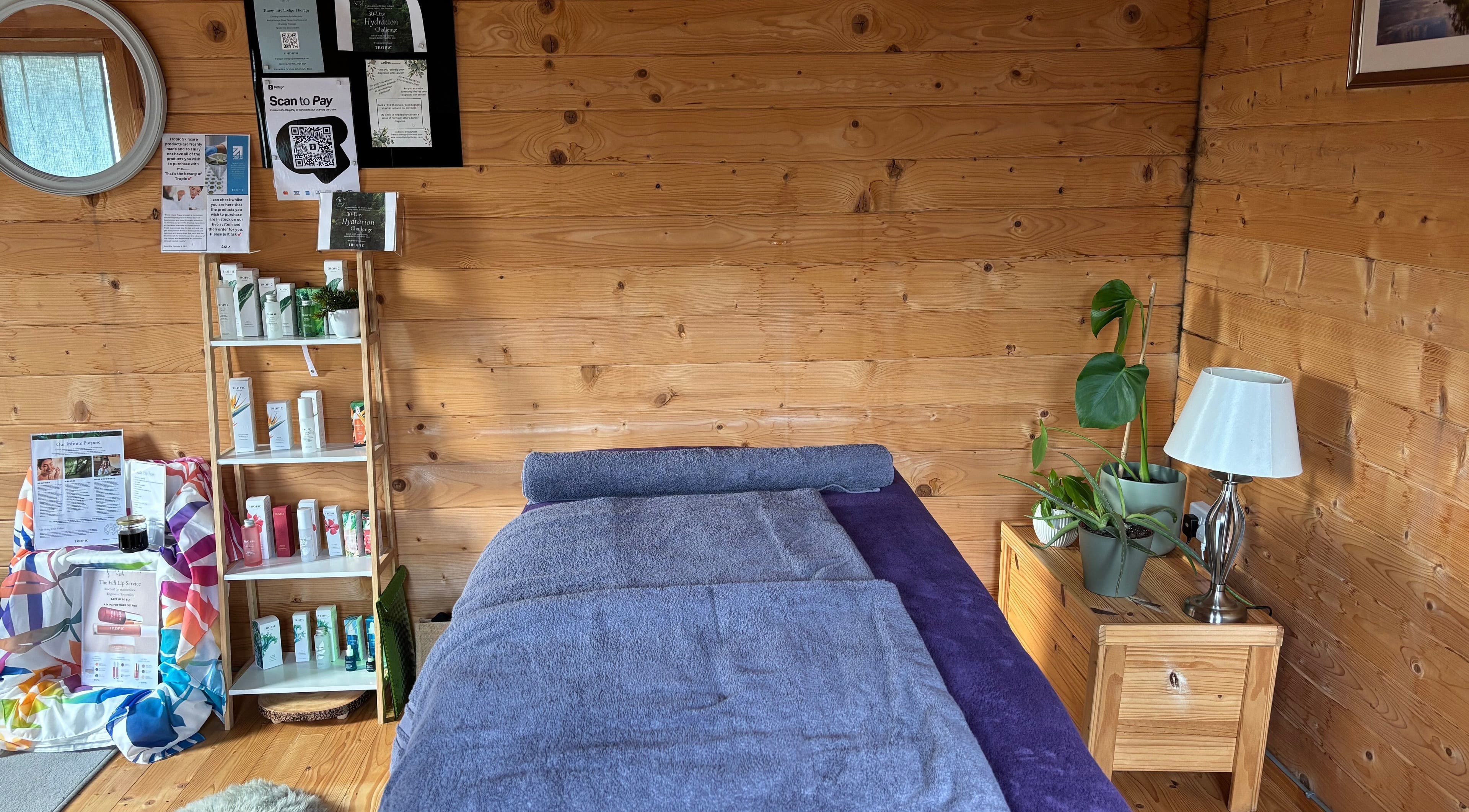 Massage room at Tranquility Lodge Therapy, Weeting, England, GB with a cozy, wooden interior and soft towels.