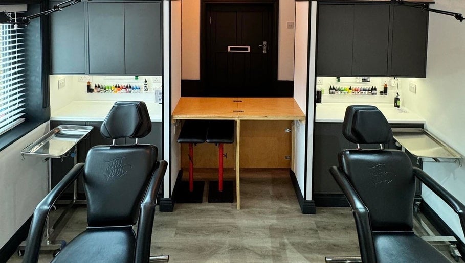 Otzi Ink's modern tattoo station in Shipley, England, GB, featuring sleek black chairs and vibrant ink bottles.