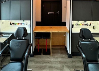 Otzi Ink's modern tattoo station in Shipley, England, GB, featuring sleek black chairs and vibrant ink bottles.