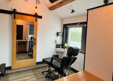 Modern studio at Otzi ink, Shipley, England with sleek chair, mirrors, and wood accents.
