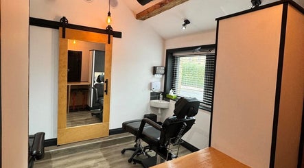 Modern studio at Otzi ink, Shipley, England with sleek chair, mirrors, and wood accents.