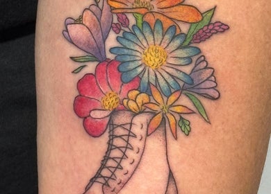 Colorful floral tattoo on arm by Otzi ink in Shipley, England, GB, showcasing vibrant artistry.