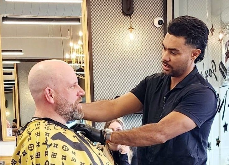 Coiffeur à Joy’s Barbershop, Beloeil, Québec, CA, coupe un client dans un salon moderne et élégant.