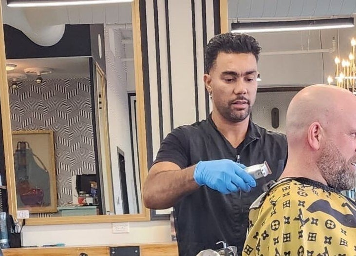 Coiffeur à Joy’s Barbershop, Beloeil, Québec, CA, en pleine coupe de cheveux pour un client.
