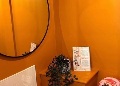 Warm orange interior with round mirror at Alexia Constantin Beauty, Hereford, England, GB. Features plant decor.