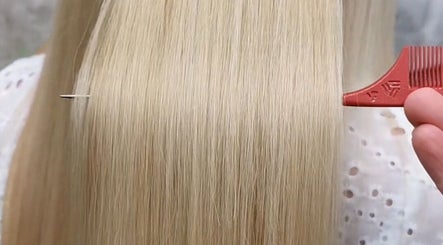 A hairstylist at Pamela Connor in Dundee, Scotland, GB expertly combs sleek, straight blonde hair.