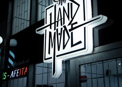 Cartel iluminado de All Handmade Barbería en Bogotá, Cundinamarca, CO, mostrando estilo moderno.