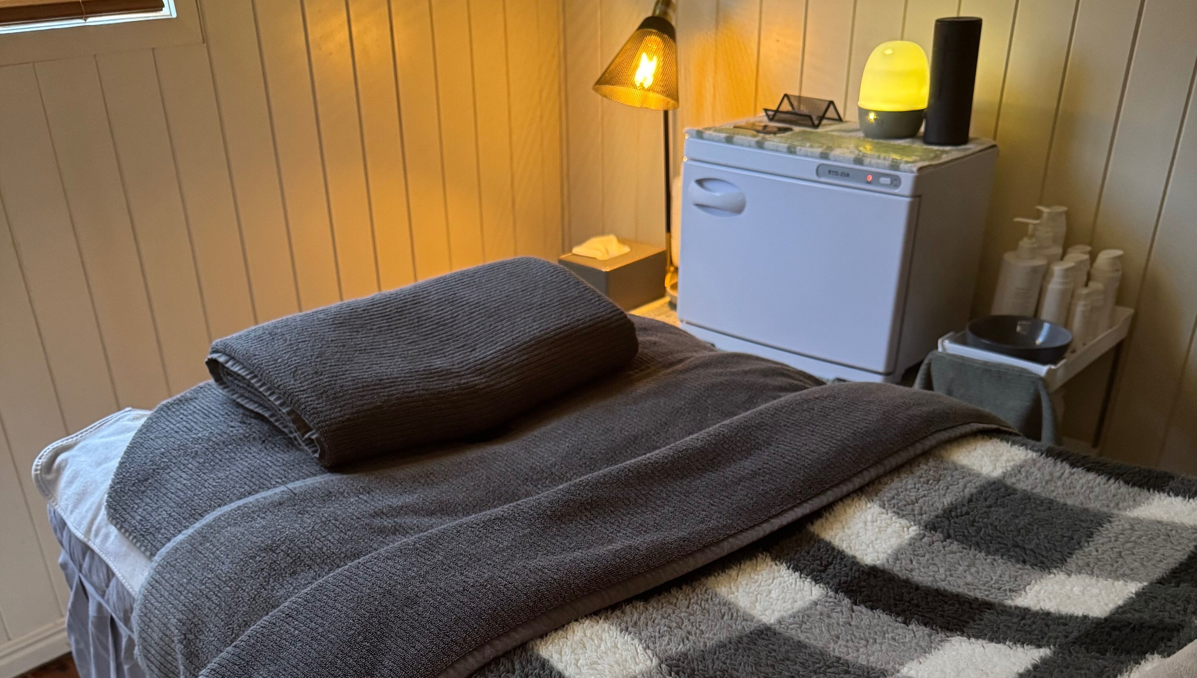 Relaxing treatment room at Beneath The Skin - Port Macquarie, New South Wales, AU with soft lighting and towels.