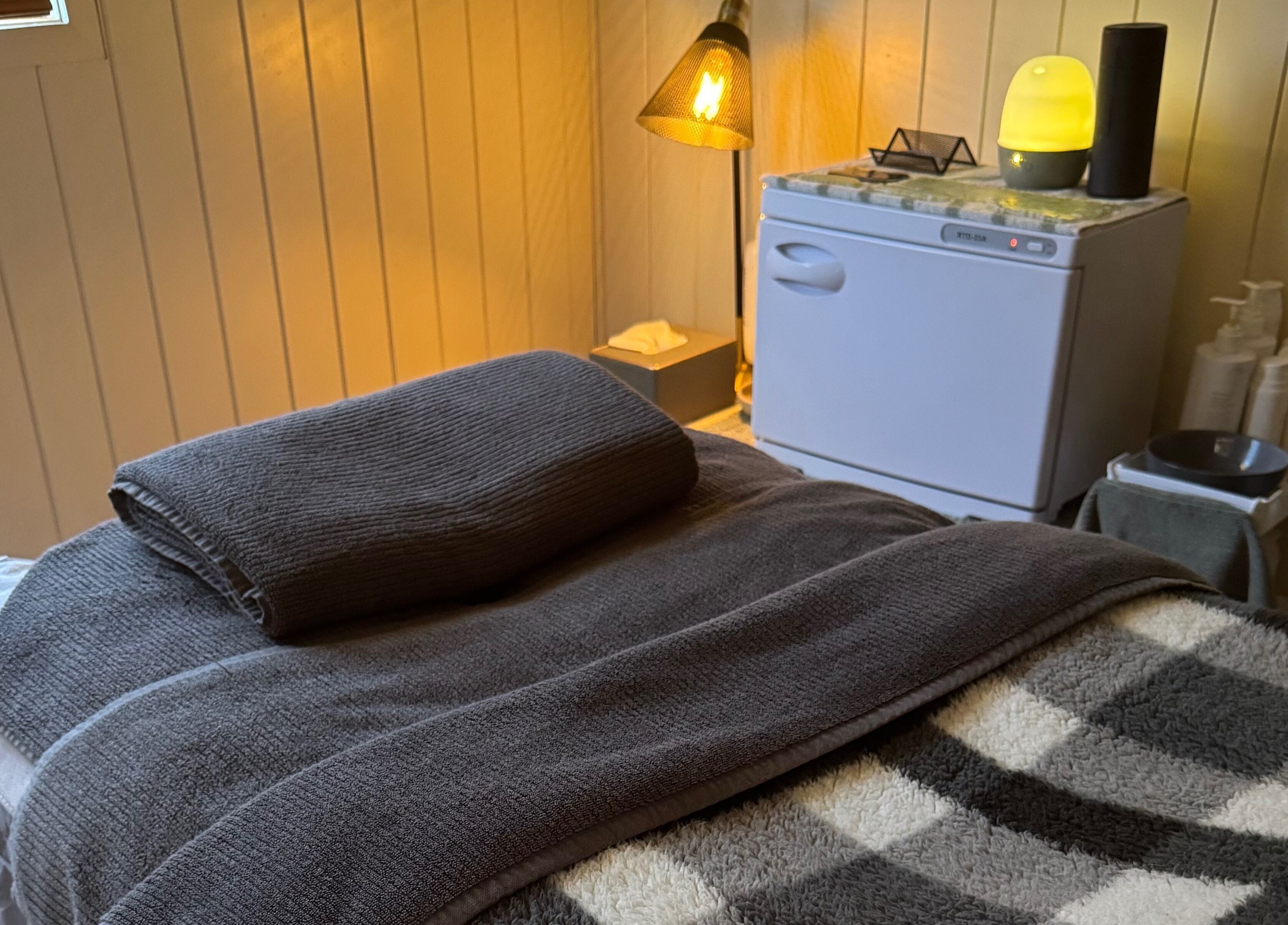 Relaxing treatment room at Beneath The Skin - Port Macquarie, New South Wales, AU with soft lighting and towels.