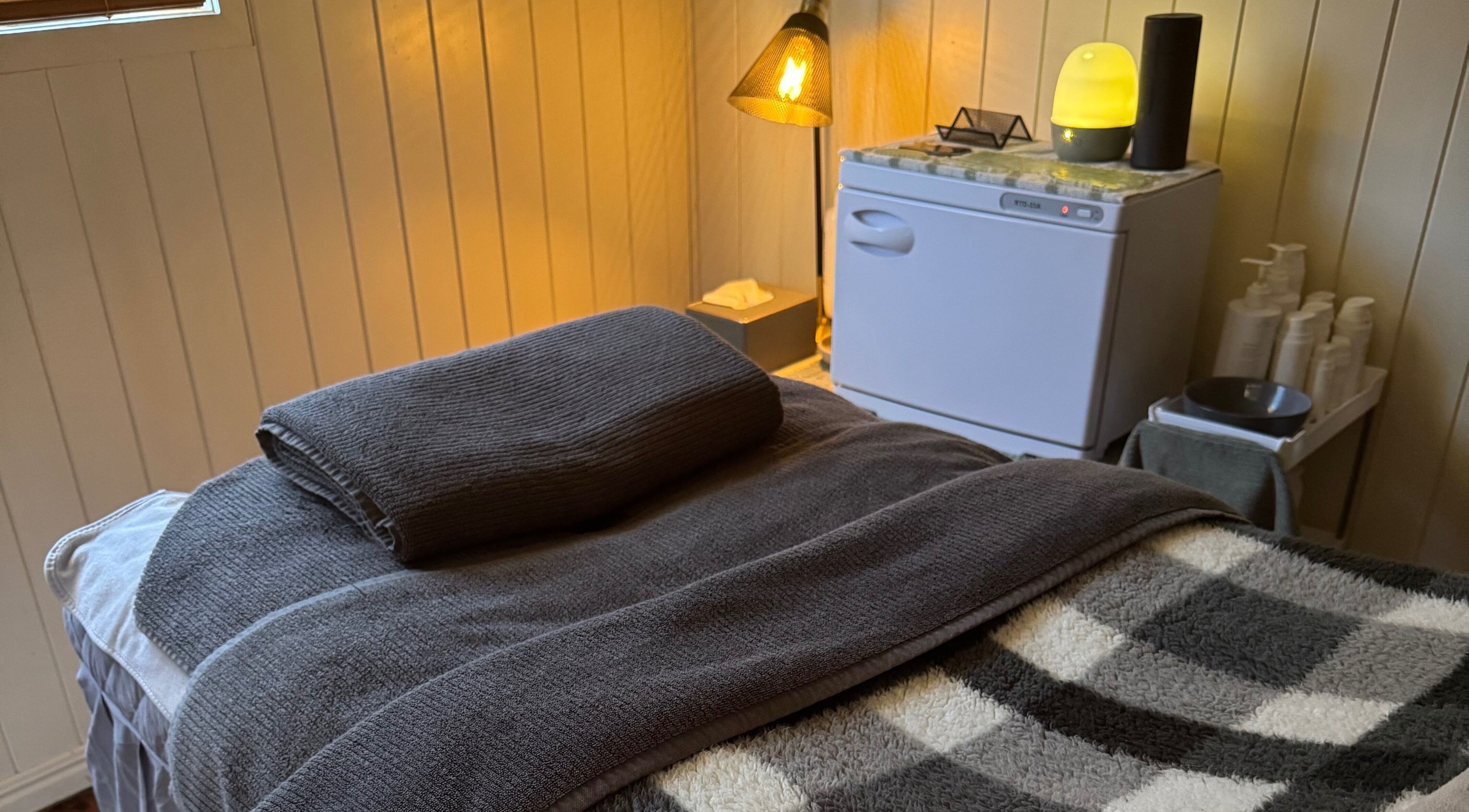 Relaxing treatment room at Beneath The Skin - Port Macquarie, New South Wales, AU with soft lighting and towels.