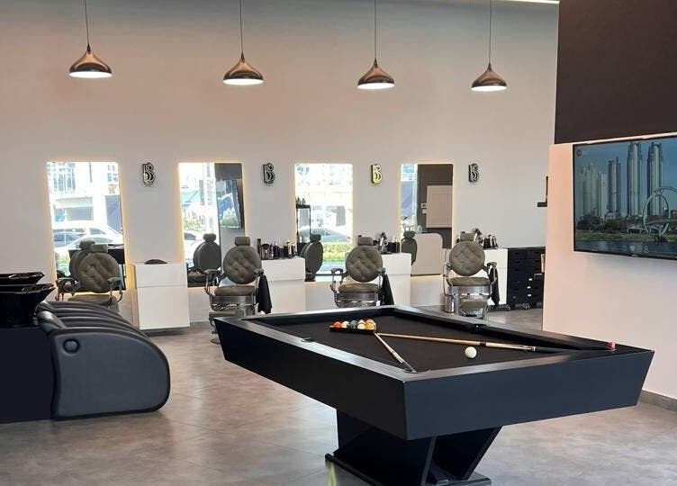 Modern interior of Barber Bliss L.L.C in Dubai, Dubai, AE featuring stylish barber chairs and a pool table.