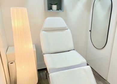 Sala de tratamento elegante na BT Nails e Estética, Lisboa, Lisboa, PT, com cadeira branca e iluminação suave.