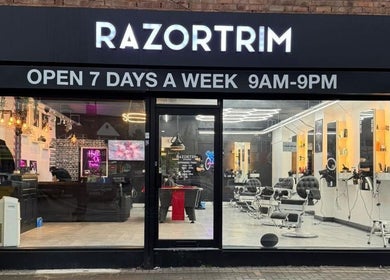 Front view of Razortrim showing lit signage and modern salon interior, located in Birmingham, England, GB.
