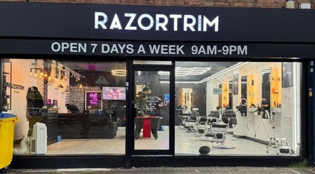 Front view of Razortrim showing lit signage and modern salon interior, located in Birmingham, England, GB.