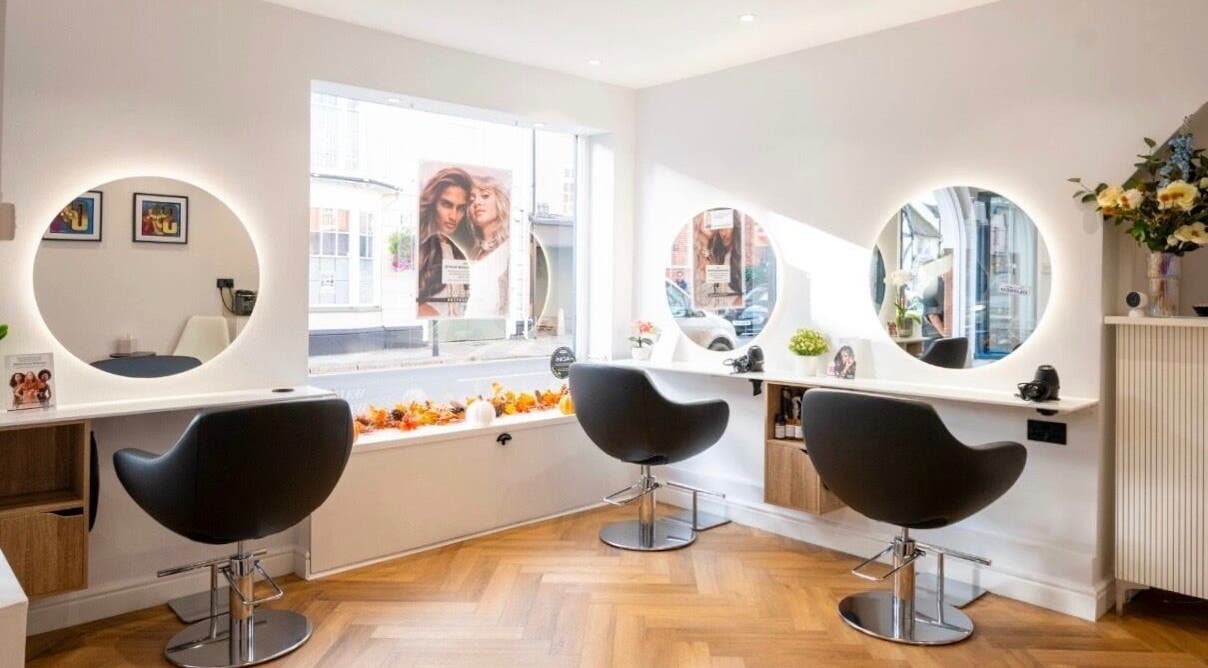 Modern salon interior at Adrian J Hairdressing in Henley-on-Thames, England, GB, featuring stylish mirrors and chairs.