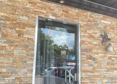 Chic stone facade of Sage Blair Beauty in San Fernando, TT with ornate lighting and glass doors.