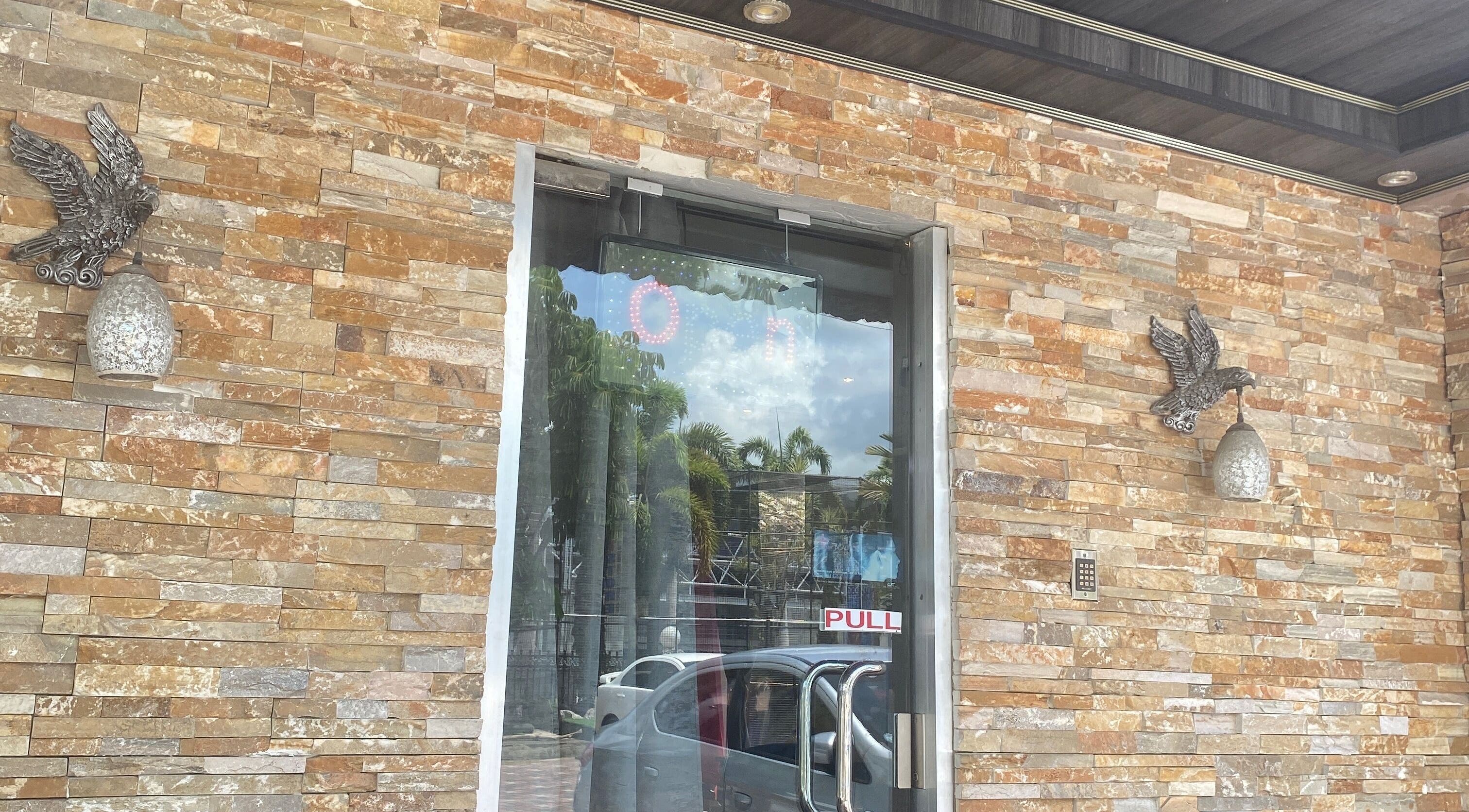 Chic stone facade of Sage Blair Beauty in San Fernando, TT with ornate lighting and glass doors.