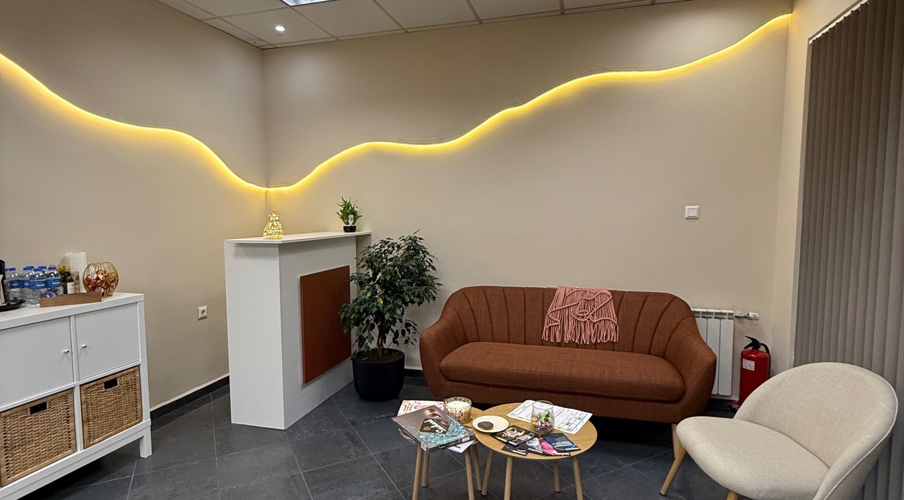 Модерен кът за изчакване в Milenails, София, Софийска област, BG с удобен диван и растения.